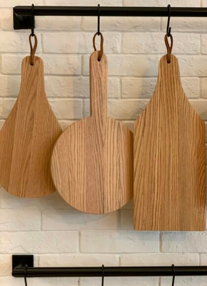 Three distinctive wooden cutting boards hanging on a kitchen wall for decorative and practical use.